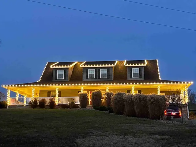 Elegant home with white Christmas lights outlining the roofline and windows
