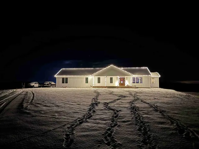 White home in the snow with roofline Christmas lights
